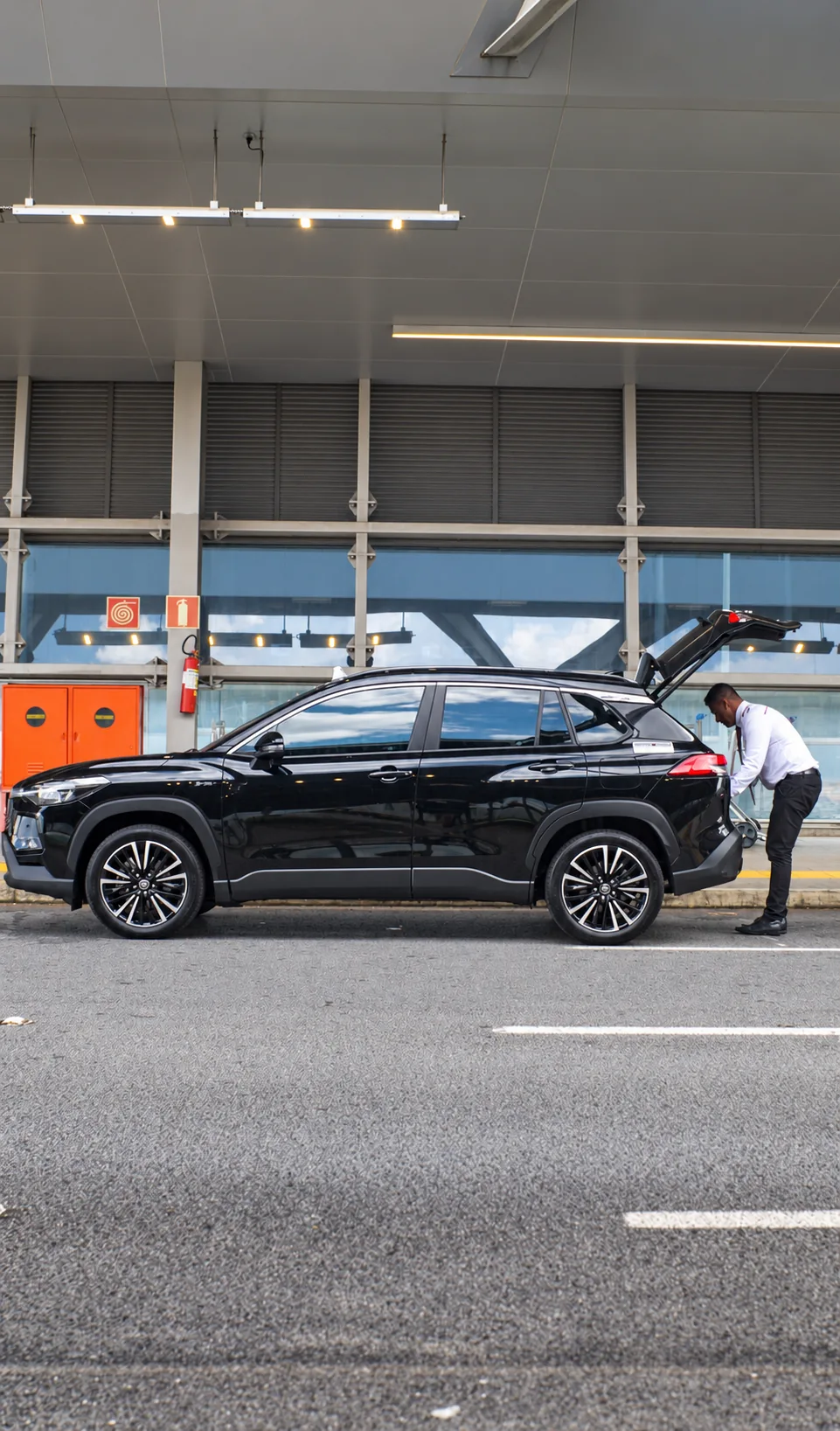 Motorista ao lado de um veículo da Coopertáxi no terminal do aeroporto