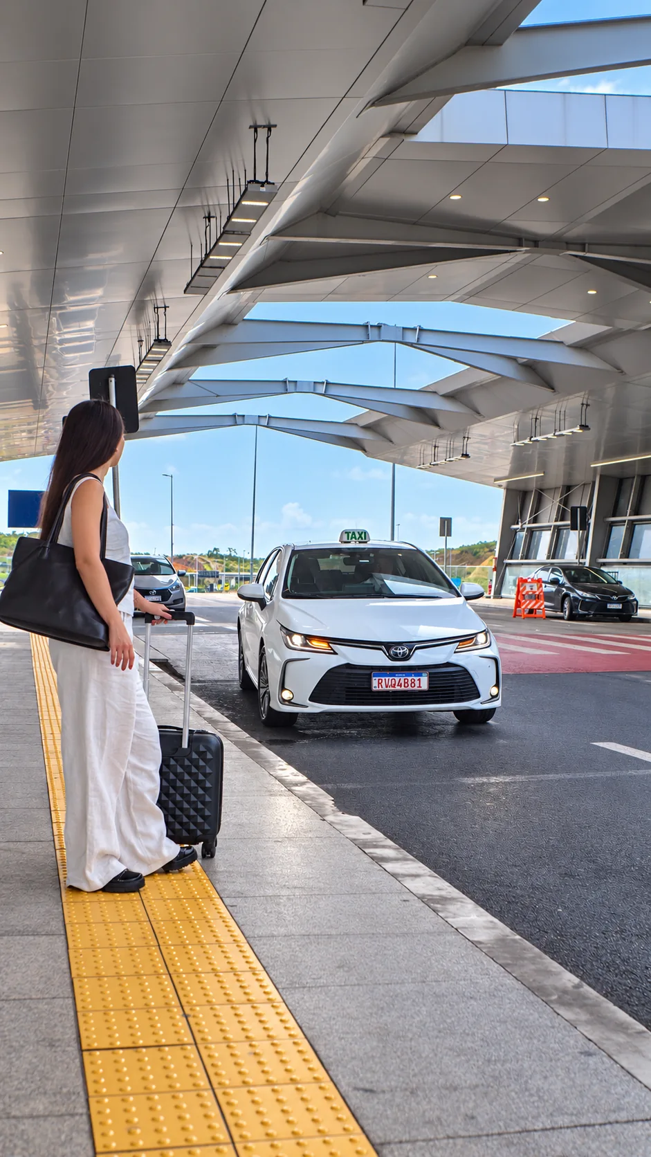 Passageira com sua mala aguardando um táxi no aeroporto